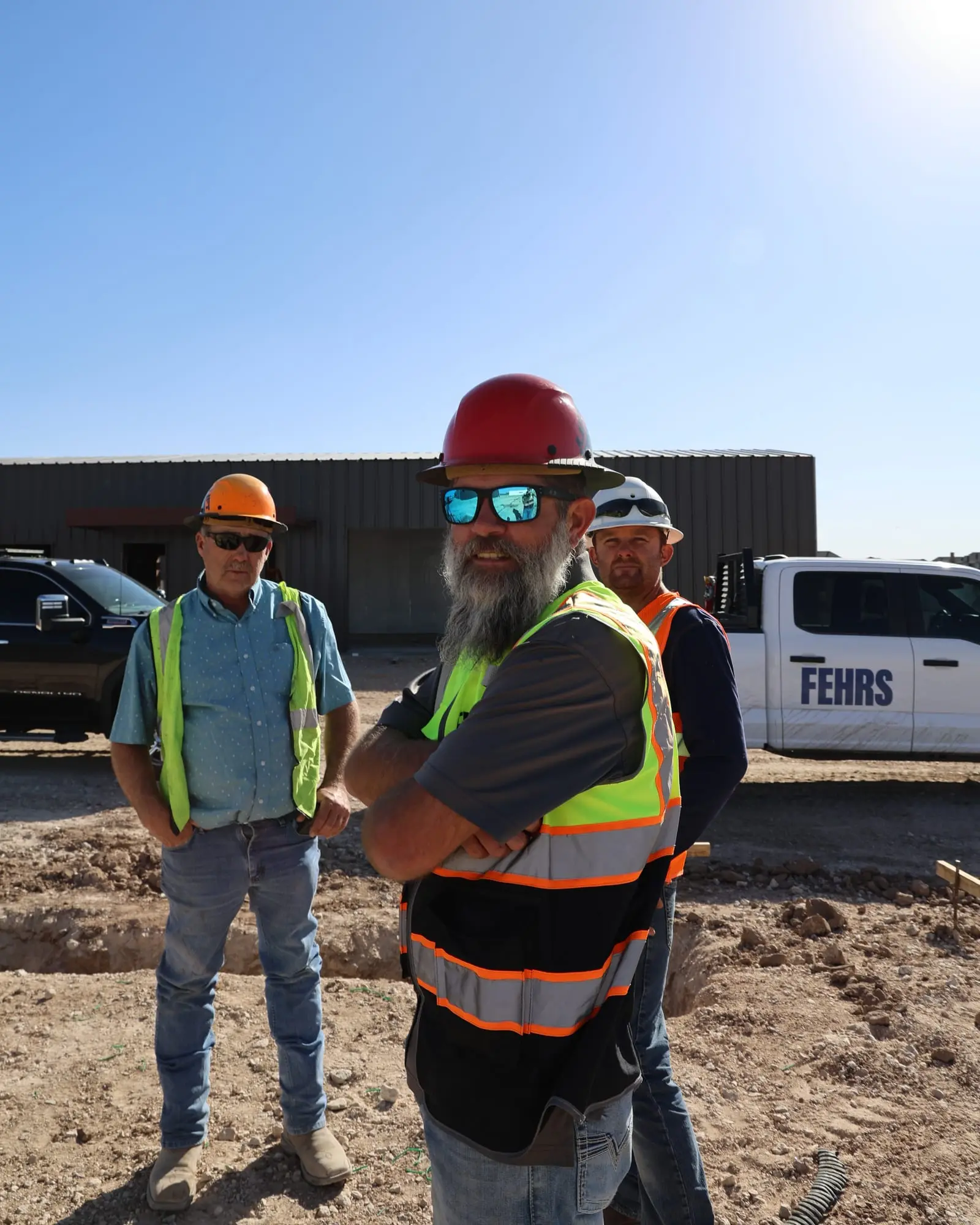 Three Precision Screeding crew members in hard hats and safety vests standing on a jobsite