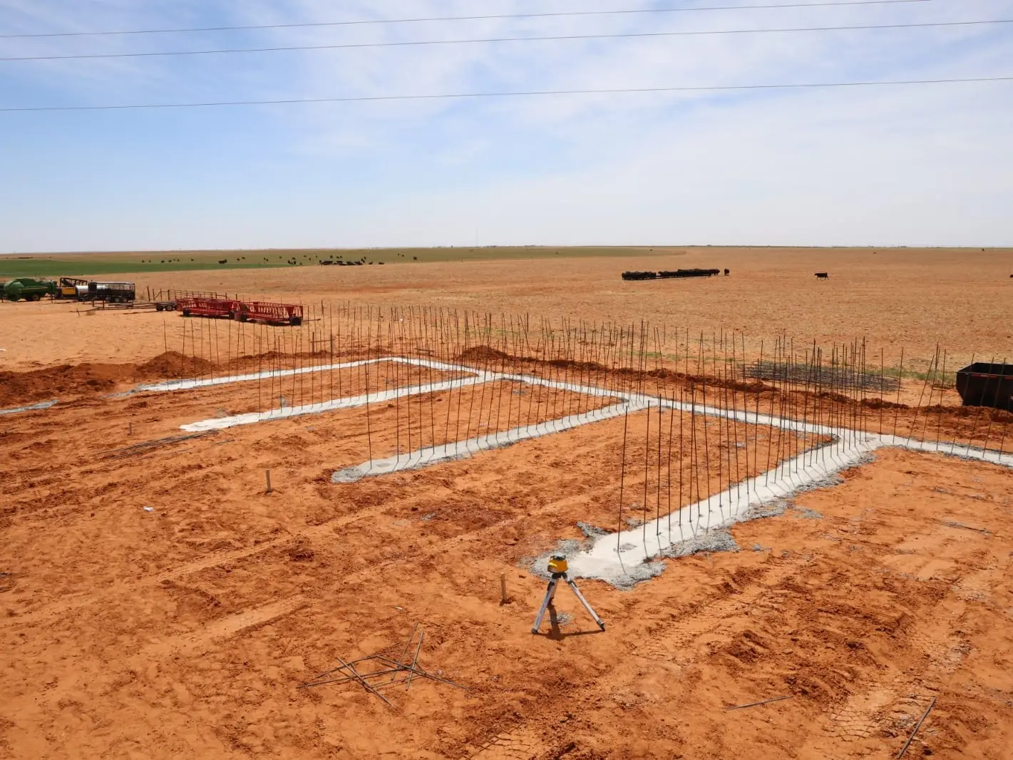 Poured concrete footings with vertical rebar dowels set out for stem walls on an open site