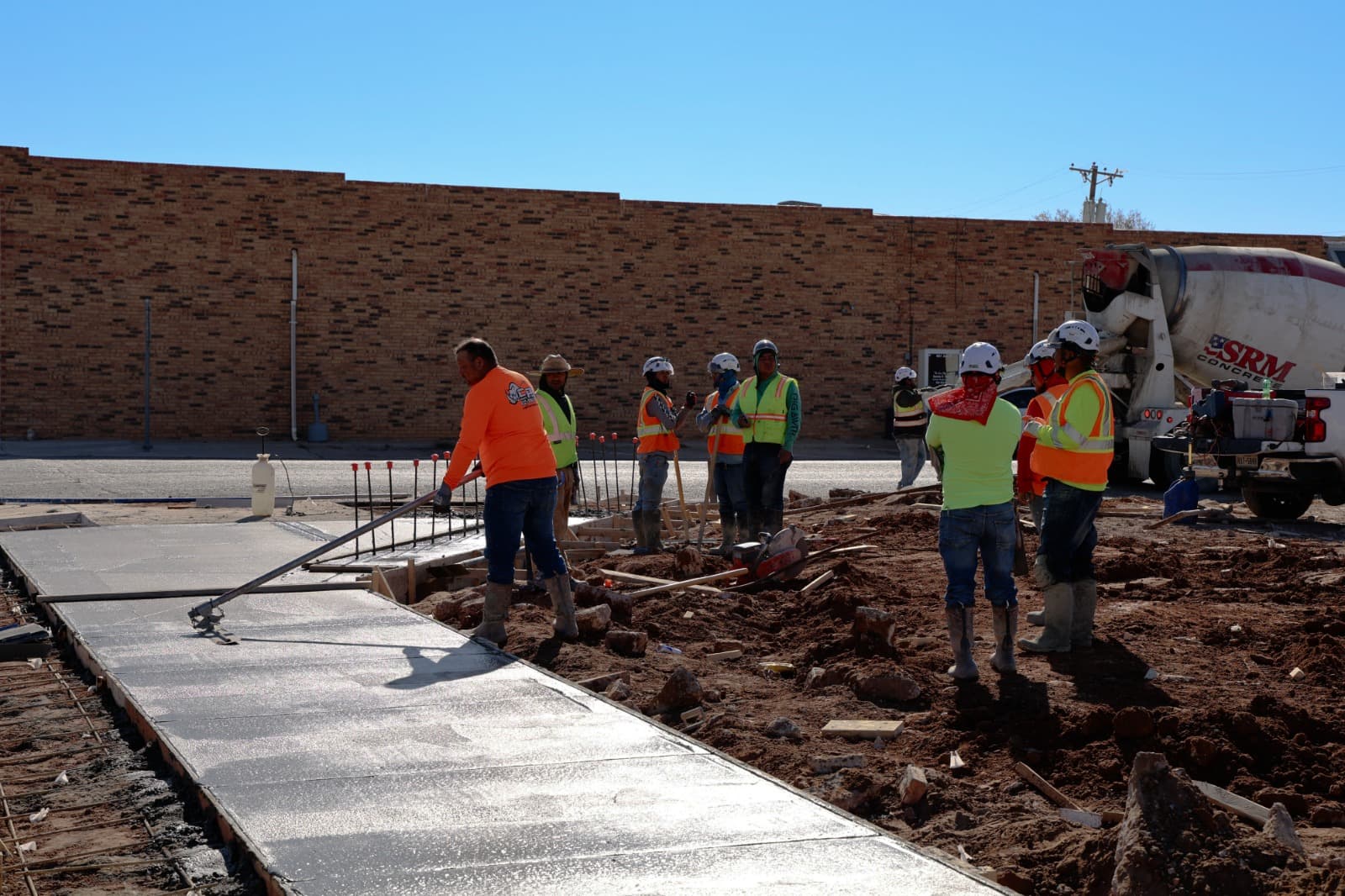 Crew pouring and finishing concrete flatwork on a commercial building site