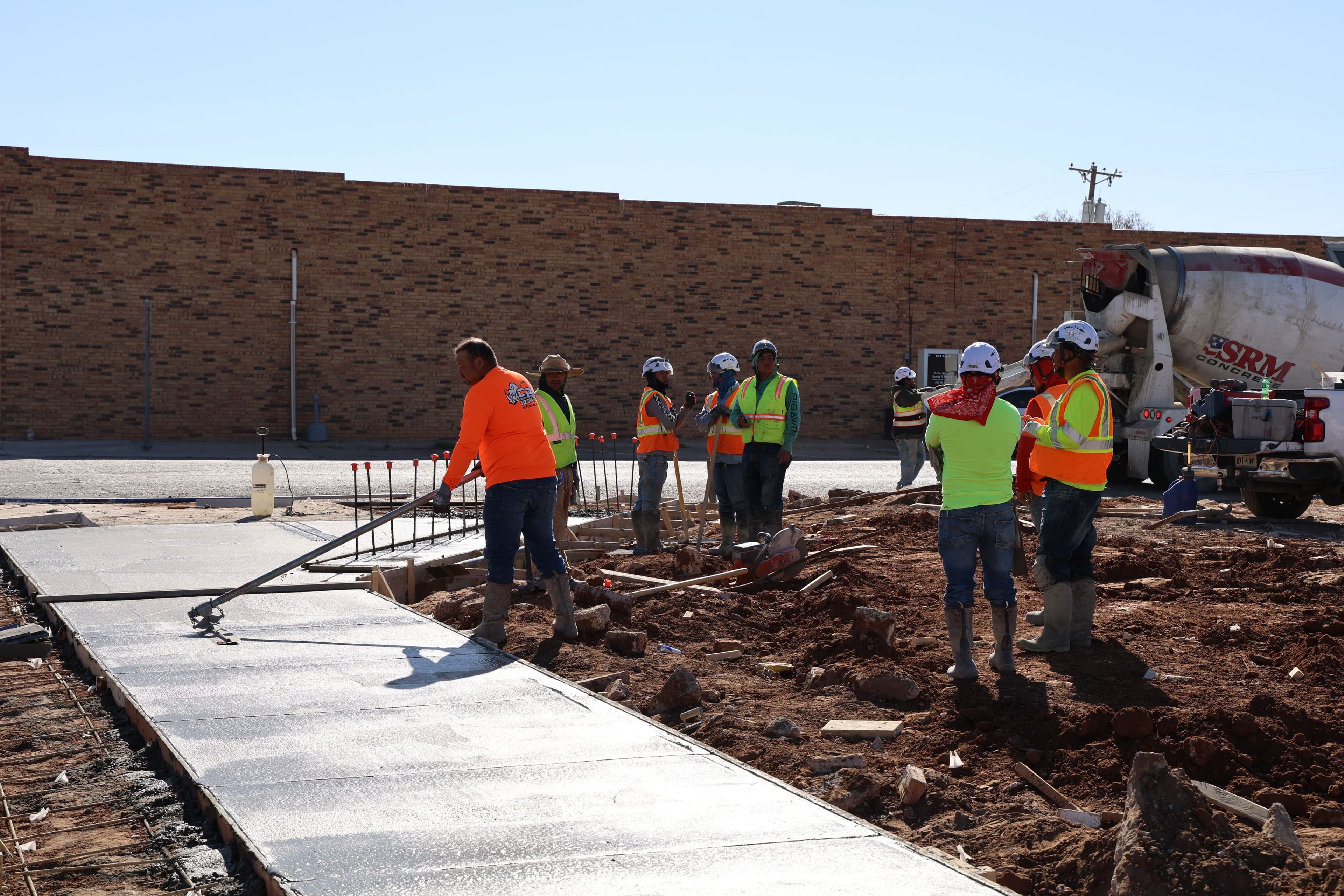 Crew pouring and screeding concrete for a commercial building slab